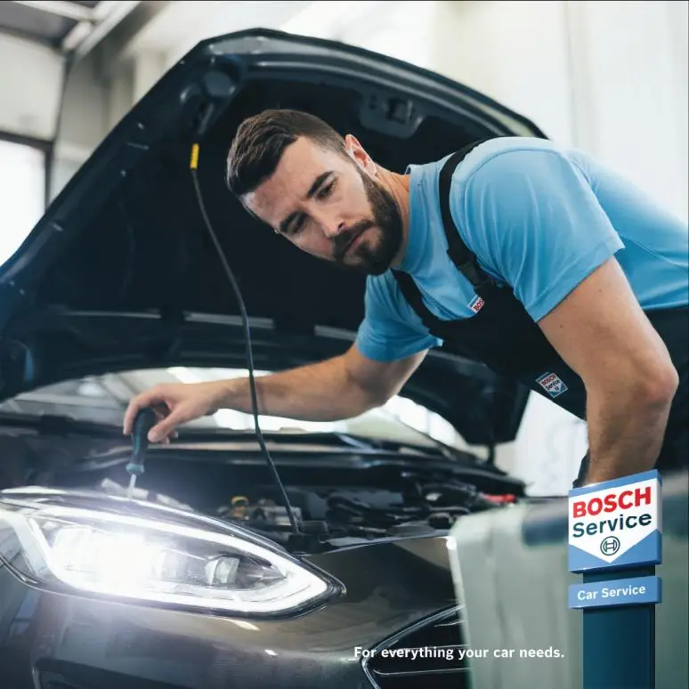 Mechanic checking a car under the bonnet with Bosch Car Service sign Alan Aston Motor Engineers