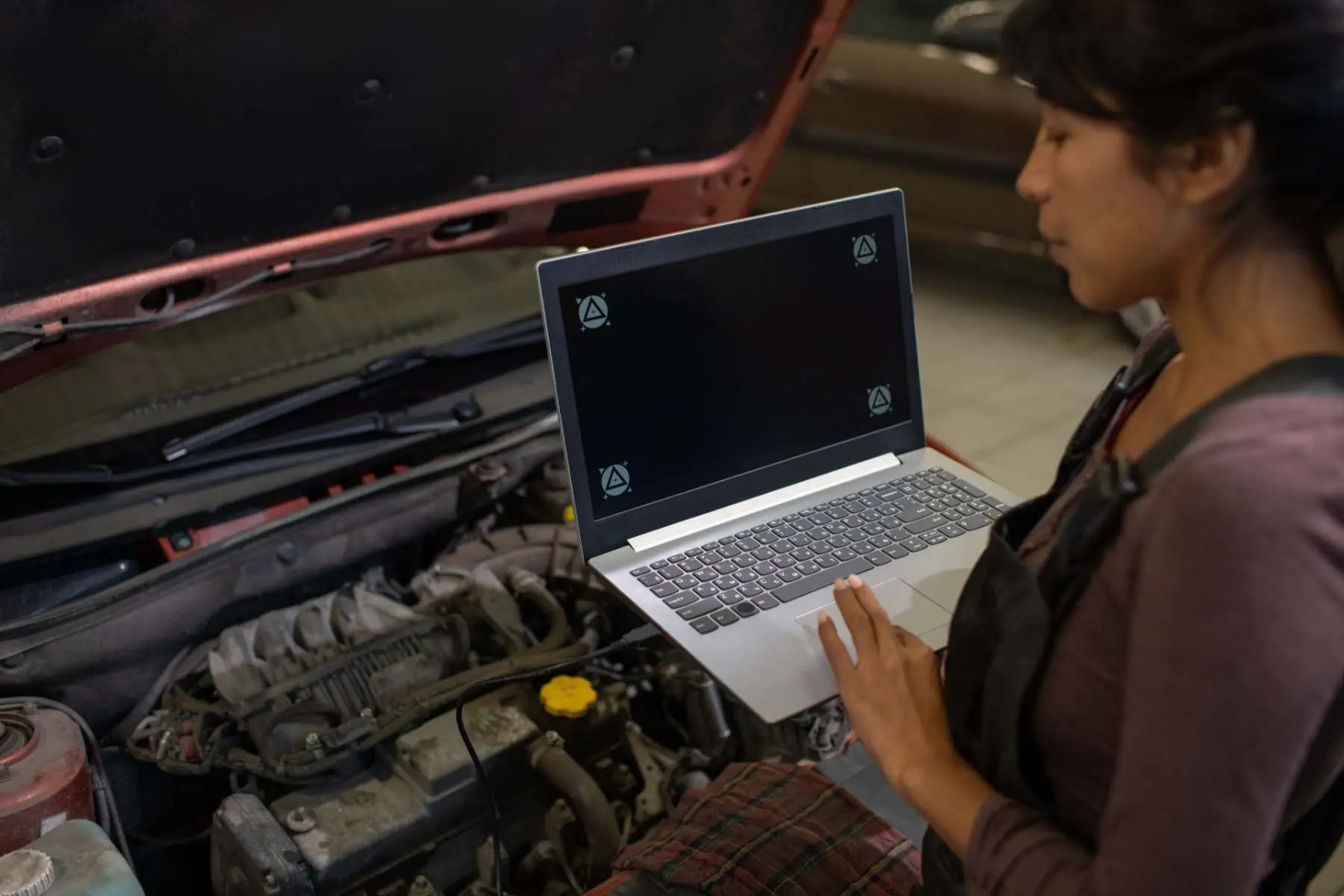 Technician running vehicle diagnostics on a laptop beside an open bonnet Alan Aston Motor Engineers Evesham