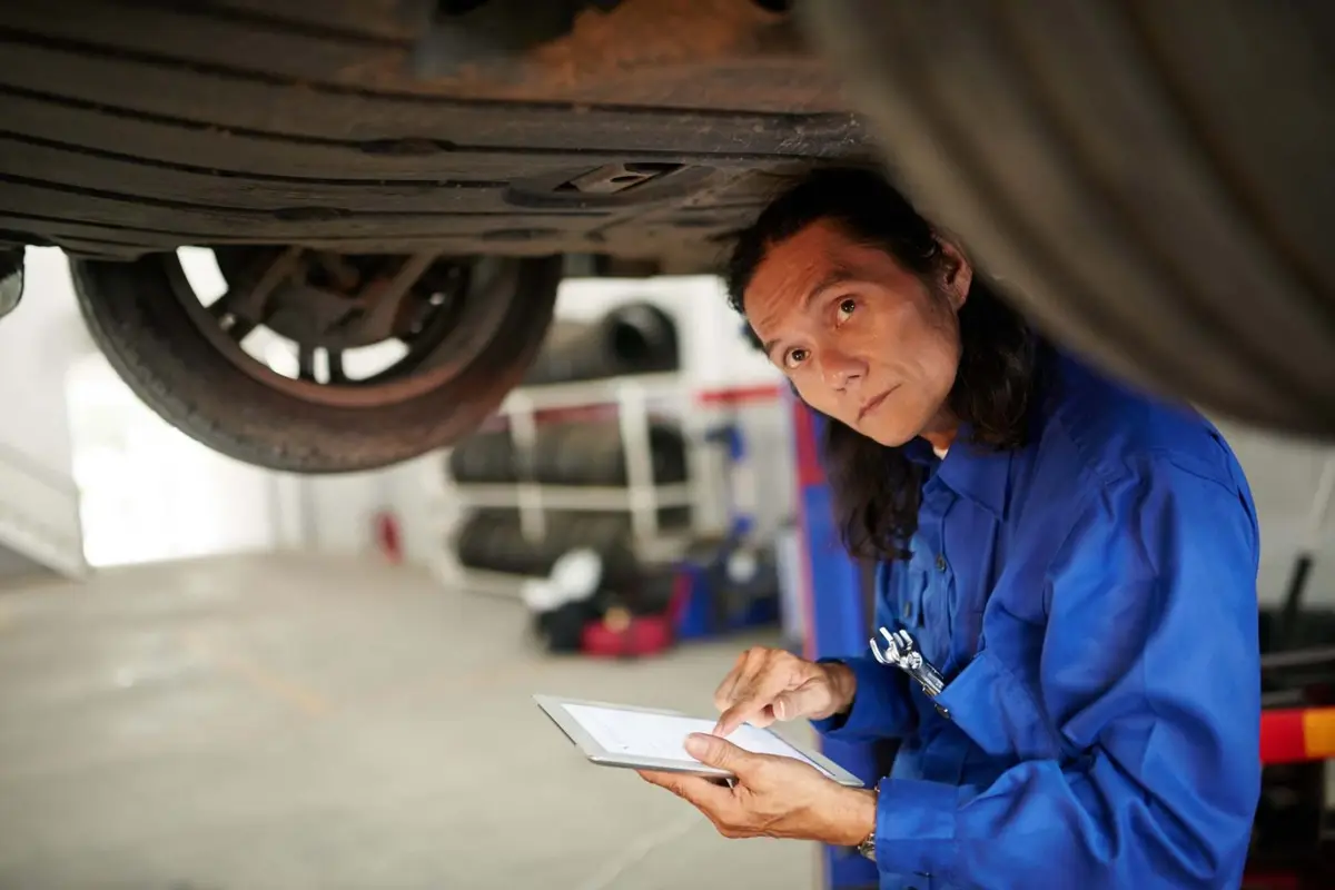Mechanic checking underneath a car during an MOT test Alan Aston Motor Engineers Evesham